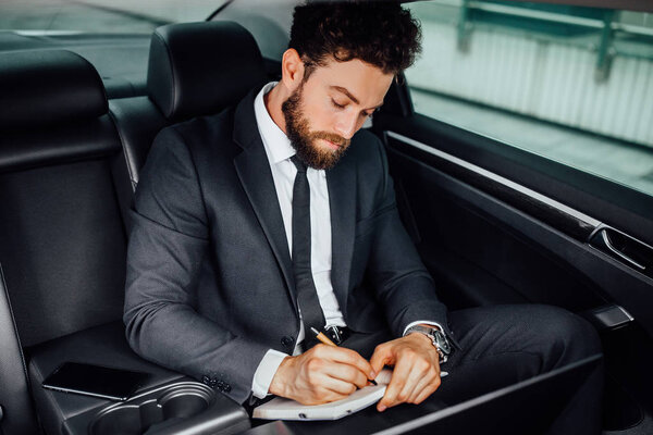 Handsome young businessman driving car, selective focus