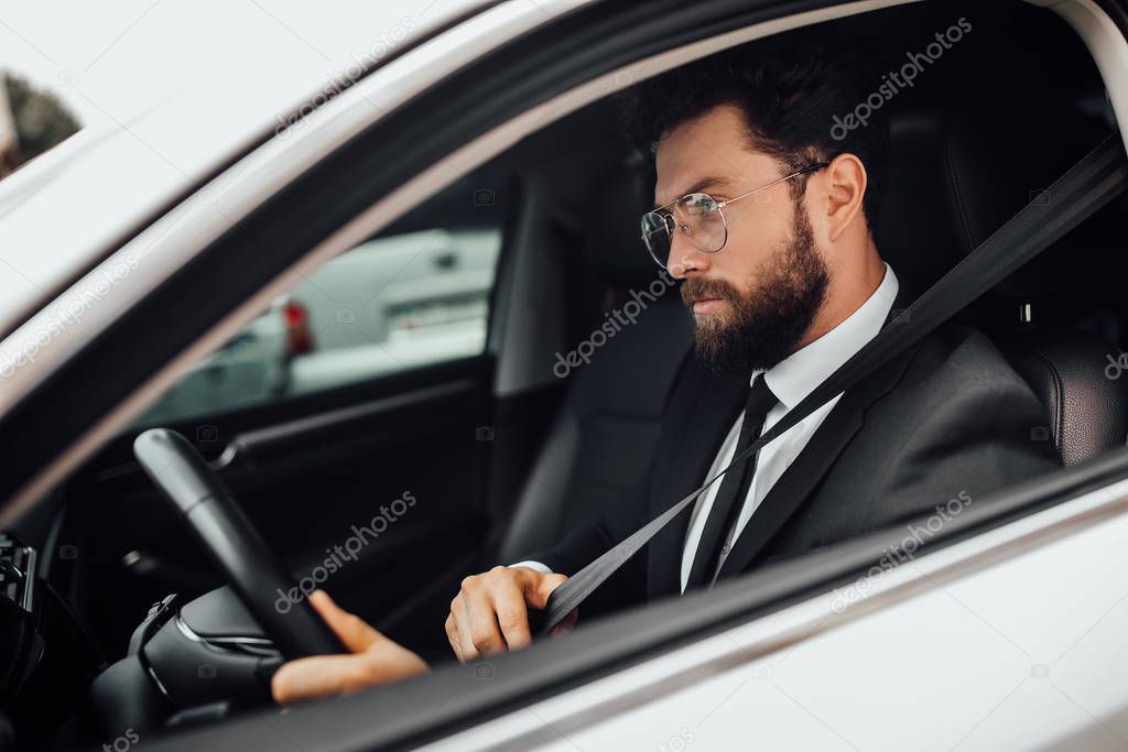 Handsome young businessman driving car, selective focus