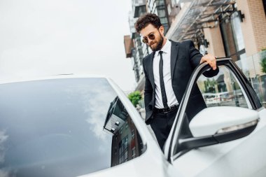 Yeni beyaz arabanın yanındaki yakışıklı genç işadamı, seçici odaklı.