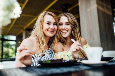 Mutlu anne ve kız yazın terasta yemek yiyor. 