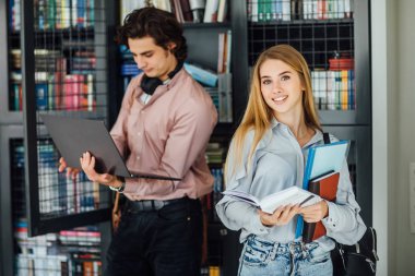 Üniversite kütüphanesinde iki öğrenci, seçici odaklanma