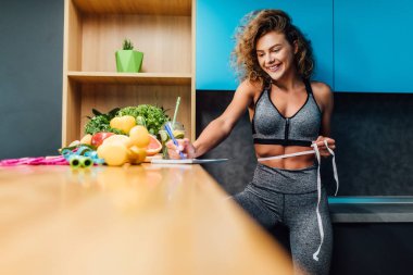 Spor kıyafetleri içinde güzel bir kadın, sağlıklı yeşil yiyecekler. 