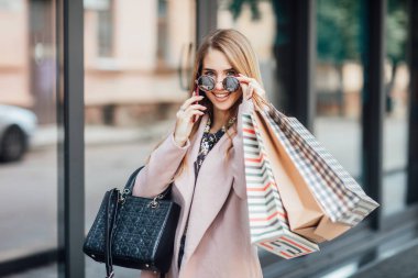 Alışveriş torbalarıyla güzel sarışın kadın, seçici bir odak noktası.