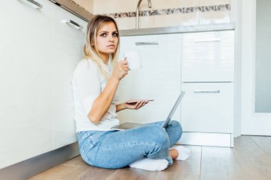 Kadın bir fincan kahve içiyor ve dizüstü bilgisayar kullanıyor, seçici odaklanma