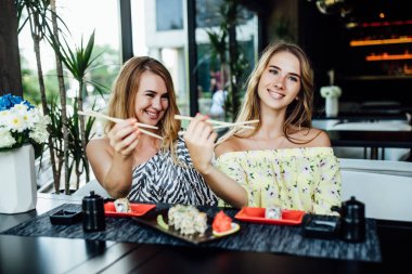 Mutlu anne ve kız yazın terasta yemek yiyor. 