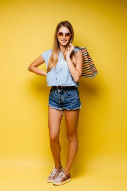 Renkli arka planda duran alışveriş çantalı güzel kadın.