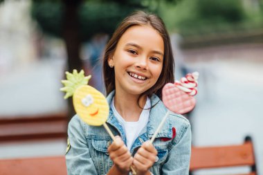 Çekici küçük kız elinde şekerlerle kameraya poz veriyor. 