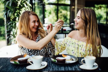 Mutlu anne ve kız yazın terasta yemek yiyor. 