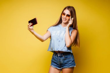 Sarı arka planda poz veren çekici kadın.