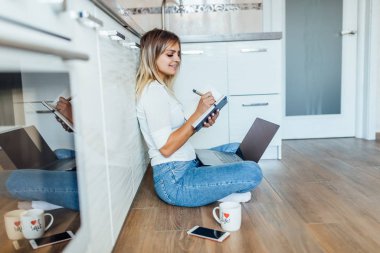 Kadın bir fincan kahve içiyor ve dizüstü bilgisayar kullanıyor, seçici odaklanma