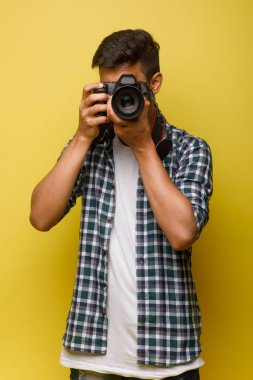 Yakışıklı ve kendine güvenen Hintli fotoğrafçı büyük profesyonel kamerayla fotoğraf çekiyor.