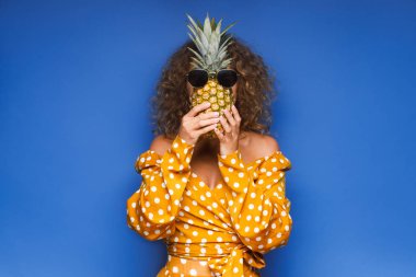 Kadın ve ananas renk arkaplanının üzerinde duruyorlar 