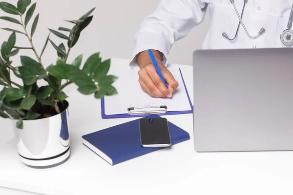 Cropped image, doctor with laptop and phone on table