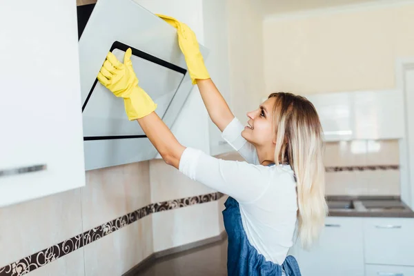 プロのクリーニング会社の若い女性が黄色い手袋のキッチンで掃除をしています — ストック写真