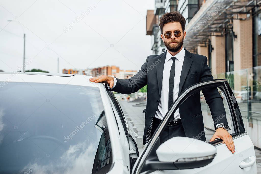 Handsome young businessman near new white car, selective focus