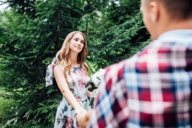 Yaz tatili, aşk, ilişki ve flört konsepti - parkta çiçek buketi olan çift.