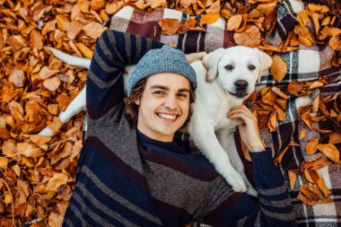 Altın labradoruyla battaniyeye uzanmış gri şapkalı mutlu adamın portresi..