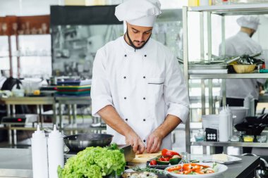 Şef aşçı, mutfaktaki ocağın yanında duruyor, tencerede yemeğinin güzel kokularını pişiriyor ve pişiriyor..