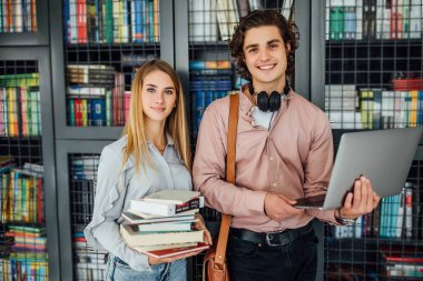 Young coworkers standing outside library and holding laptop. clipart