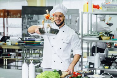 Sakallı, genç aşçı mutfakta sebze ve diğer yiyeceklerle hokkabazlık yapıyor..