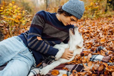Gri şapkalı çekici bir adam köpeğiyle battaniyeye uzanıyor..