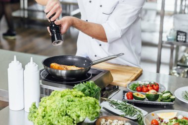 Kapatın hpoto 'yu, şef taze somon balığı hazırlıyor, malzemelerle tuz serpiyor. Buz havada donuyor. Balık yemi pişirmeye hazırlanıyorum..