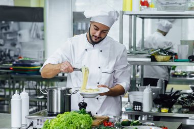 Yakışıklı, sakallı ve başarılı aşçı mutfağa spagetti hazırlıyor, Şef yemek pişiriyor, ekili resim yapıyor..