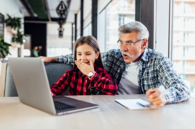 Torunuyla yaşlı adam tablet kullanıyor. Çocuğa video çağrısı yapıyor..