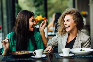 İki kız arkadaş birlikte kafede kahve içerek kahvaltı ve tatlıya kadar eğlenerek vakit geçiriyorlar. Birbirlerini yediriyorlar..