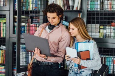 Üniversite kütüphanesinde dijital tablet kullanan iki öğrenci.