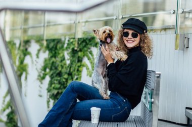Avrupa caddesinde genç bir moda kadını tasmalı iki renkli küçük bir Chihuahua köpeğiyle yürüyor. Bulutlu, ılık sonbahar bahar havası. Siyah gömlekli ve çıplak ayakkabılı bir kız. Kahve zamanı..