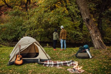 Kampta duran genç ve güzel bir çift. Çekici kadın ve yakışıklı erkek çadırın yanında birlikte dinleniyorlar..