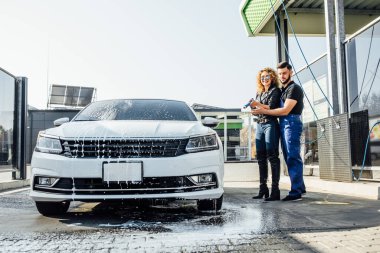 Araba yıkama, çamurdan motoru temizlemek için sprey köpüklü kadın..
