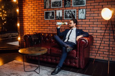 Genç bir iş adamı lüks bir dairede dergide dinleniyor..