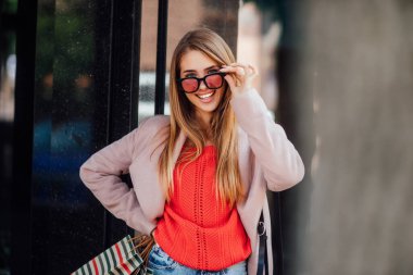 Güzel, gülümseyen bir kız, elinde poşetlerle sokakta yürürken başarılı bir alışveriş yapmaktan zevk alır..