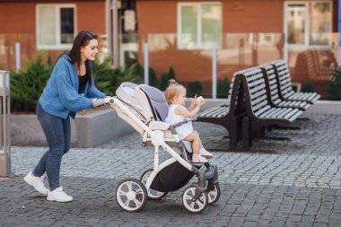 onunla yürüyen genç anne bebek ve güzel çocuk arabası içinde taşır.