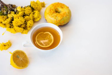 Beyaz arka planda limonlu ve çiçekli çay. Sabahları tatlı çörekler.