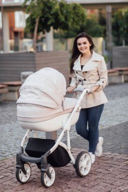 Avrupa şehir merkezinde bebek arabasıyla yürüyen güzel bir annenin portresi..