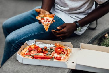 Fotoğrafı kapat. Yemek konsepti, sokakta pizza yiyen adam..