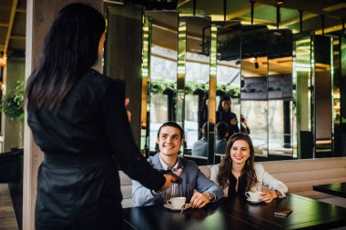 Lokantada oturan bir çiftin fotoğrafı. Adam garsonun parasını öderken..