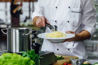 Yakışıklı sakallı aşçı mutfağa spagetti hazırlıyor, Şef yemek pişiriyor, ekili resim yapıyor..