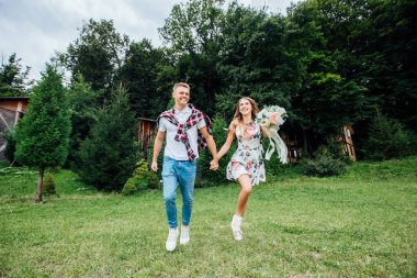 Genç bir çiftin el ele tutuşup parkta koşarken fotoğrafı. Bulanık hareket, yumuşak odaklanma.