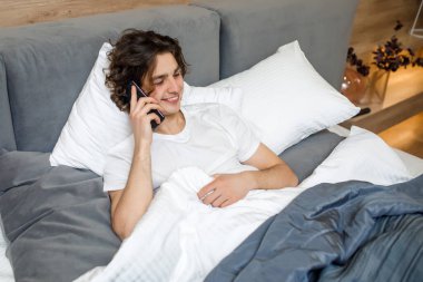 Genç adam telefonda konuşuyor, sabah erkenden, hafta sonu konsepti..