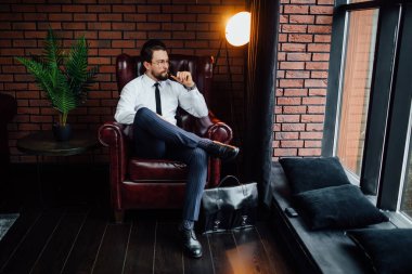 Milyoner adam lüks odadaki kanepede otururken dinleniyor ve dinleniyor. Puro içen yakışıklı adam..