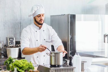 Beyaz önlüklü genç adam makarna hazırlıyor, İtalyan spagettisi için su kaynatıyor..