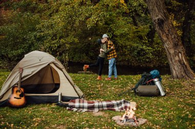 Genç ve güzel bir çift kampta sarılıyor. Çekici kadın ve yakışıklı erkek çadırın yanında birlikte dinleniyorlar..