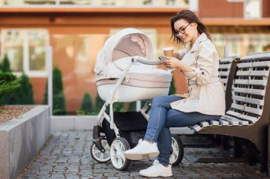 Bebek arabasında yeni doğmuş bir bebekle başarılı bir anne evinin yakınında bir sokakta çay ya da kahve içer ve telefon tutar. Bir bebeği olan modern bir anne..
