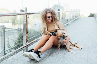 Güzel beyaz bir kadınla küçük bir köpek parkta oyun oynayıp eğleniyor..