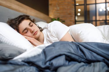 Barışseverlik kavramı. Modern odada yatakta uyuyan yakışıklı genç adam..