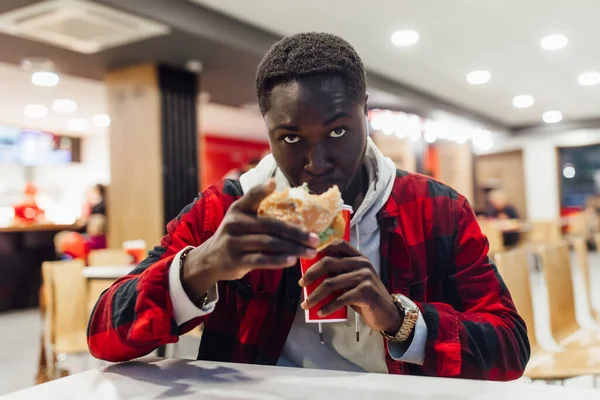 Lunch Cafe African Man Red Casual Shirt Eats Burger Drinking — Stock Photo, Image